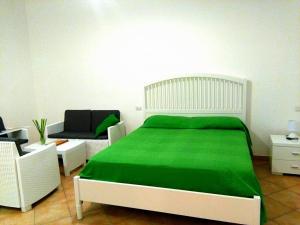 a white bedroom with a green bed and a couch at A Sorrento in Sorrento