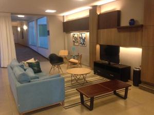 a living room with a blue couch and a tv at Orion Hotel in Itumbiara