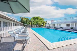 a swimming pool with chaise lounge chairs next to a building at Days Inn by Wyndham Miami Airport North in Miami +36 photos