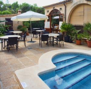 una piscina con mesas, sillas y una sombrilla en Villa Lorenzo, en Cala Figuera
