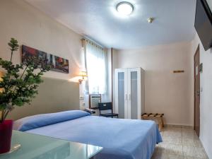Un dormitorio con una cama azul y una mesa de cristal en Hotel Legazpi, en Murcia