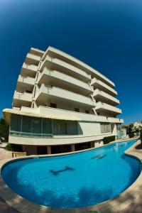 un bâtiment avec une piscine en face d'un bâtiment dans l'établissement Hotel Alexander, à Cattolica