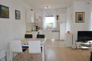 a white kitchen with a table and white chairs at Apartment Nena in Krk