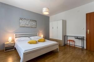 a bedroom with a white bed with two yellow pillows at Marijana Bol Apartments in Bol