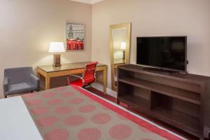 a hotel room with a flat screen tv and a desk at Ramada by Wyndham Miami Springs/Miami International Airport in Miami