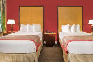 two beds in a hotel room with red walls at Ramada by Wyndham Miami Springs/Miami International Airport in Miami