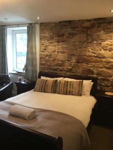 een bed in een kamer met een stenen muur bij The Ship Inn in Invergordon