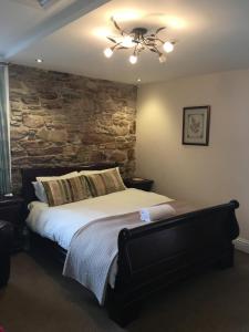 een slaapkamer met een groot bed en een stenen muur bij The Ship Inn in Invergordon