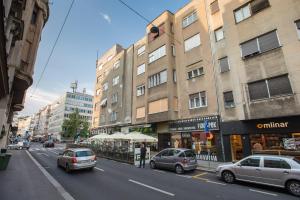 uma movimentada rua da cidade com carros estacionados em frente aos edifícios em Apartman Pierre em Zagreb