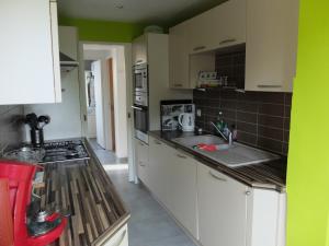 a kitchen with white cabinets and a green wall at BAIE MT ST MICHEL VILLA Caprice Rdc 50 m Mer Prés Plage DDAY 7pers in Jullouville-les-Pins