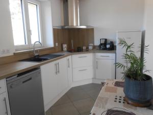 une cuisine avec des armoires blanches et une plante en pot dans l'établissement Maison Brix, à Brix