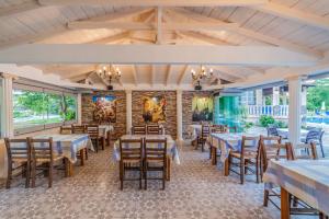 a dining room with tables and chairs and windows at Sintrivanis Resort Beach in Paralía Skotínis