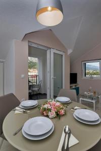 una mesa de comedor con platos y flores. en Apartments Beso en Makarska