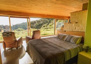 a bedroom with a bed and two chairs and a large window at Golden Bay Hideaway in Takaka
