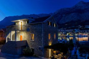 een huis 's nachts met bergen op de achtergrond bij Apartments Beso in Makarska