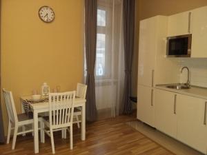 una cocina con mesa y sillas y un reloj en la pared en Apartment Vltavska B en Praga