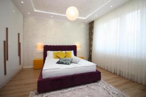 a bedroom with a bed with white sheets and yellow pillows at Radiceva Apartment in Sarajevo