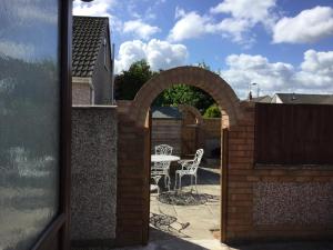 a patio with an archway and a table and chairs at Canterbury Cottage in Prestatyn