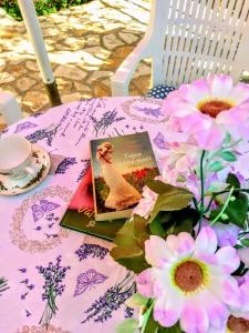 een boek bovenop een tafel met bloemen bij Jadrija II House for rest in Jadrija