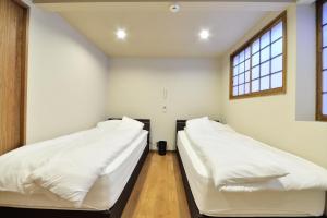 2 Betten in einem Zimmer mit 2 Fenstern in der Unterkunft Comfortable House In Fushimi in Kyoto