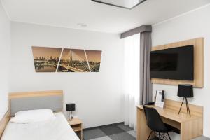 um quarto com uma cama, uma secretária e uma televisão em Waw Hotel Airport Okęcie em Varósvia