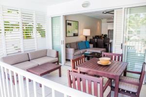 een veranda met een bank en een tafel en stoelen bij 3123 BEACH CLUB PARADISE in Palm Cove