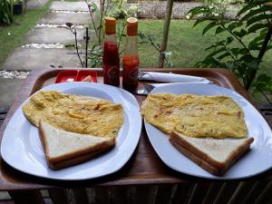 two plates of food on a table with two slices of bread at Herry Homestay Kuta Lombok in Kuta Lombok