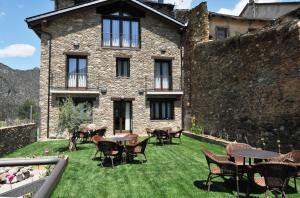 un patio con mesas y sillas frente a un edificio en Casa Rural La Comella, en Tirvia