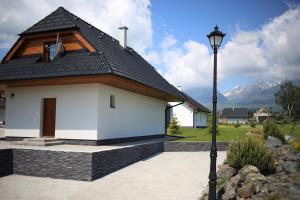 eine weiße Kirche mit einem schwarzen Dach und einem Straßenlicht in der Unterkunft Villa Mia in Stará Lesná