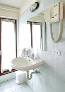 La salle de bains blanche est pourvue d'un lavabo et d'un miroir. dans l'établissement La Rotonda, à Pergine Valsugana