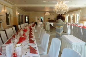uma longa sala de jantar com mesas brancas e cadeiras brancas em Historisches Landhotel Studentenmuehle em Nomborn