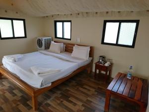 una camera da letto con un grande letto con lenzuola bianche e finestre di Hiranya Resorts a Daulatābād