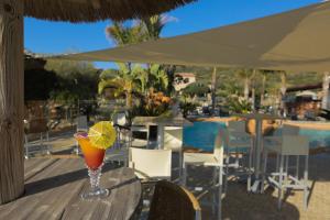 un drink seduto su un tavolo accanto alla piscina di Résidence & SPA Marina d'Arone a Piana