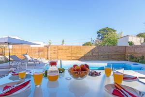 a table with a bowl of fruit and glasses of orange juice at Aphrodite in Adelianos Kampos