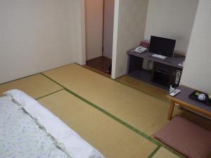 a room with a bed and a desk with a television at Uokagi Ryokan in Nagoya