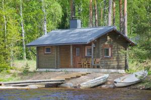 una cabaña de madera con dos barcos delante en Matkailutila Lahdelma en Pertunmaa