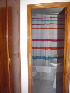 a bathroom with a striped shower curtain and a toilet at Hostal Mini Golf in Los Caños de Meca +42 photos