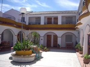 a large white building with a courtyard with plants at Hostal Mini Golf in Los Caños de Meca