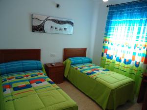 Un dormitorio con dos camas y una ventana. en Hostal Los Claveles, en Baena