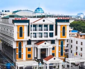 a large white building with orange and yellow trim at Rg Royal Hotel in Bangalore