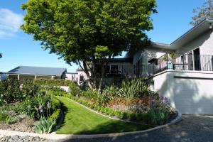 a house with a garden and a tree in front of it at For Puffed Pedallers in Mapua