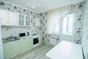 - une cuisine avec des placards blancs et du papier peint floral dans l'établissement Apartments on 7/1 Sarayshyq, à Astana