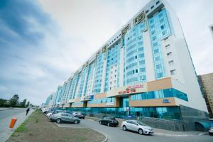 un grand bâtiment avec des voitures garées dans un parking dans l'établissement Apartments on 7/1 Sarayshyq, à Astana