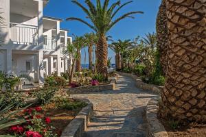 a resort pathway with palm trees and houses at Happy Days Beach Hotel in Georgioupolis