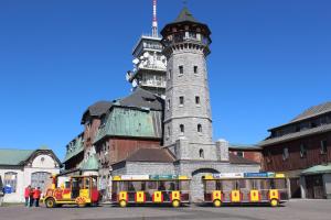 a train in front of a building with a tower at Apartments Sport Fudel in Kurort Oberwiesenthal