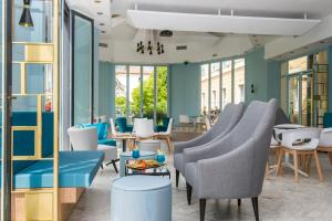 a lobby with blue and white chairs and tables at Hôtel Miléade L'Orangeraie - Menton in Menton