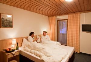 two women are sitting in bed under the sheets at Gasthof Hochsteg in Finkenberg