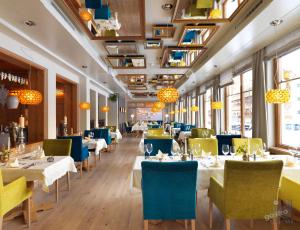 un restaurante con mesas blancas, sillas azules y ventanas en Hotel der Wiesenhof, en Pertisau