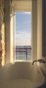 南灣的住宿－迷路小章魚小旅館，带窗户的浴室设有大浴缸