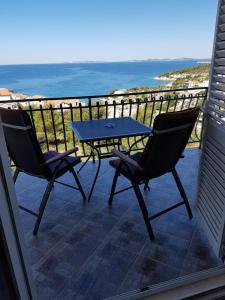 einen Tisch und zwei Stühle auf einem Balkon mit Meerblick in der Unterkunft Apartments Angela in Primošten